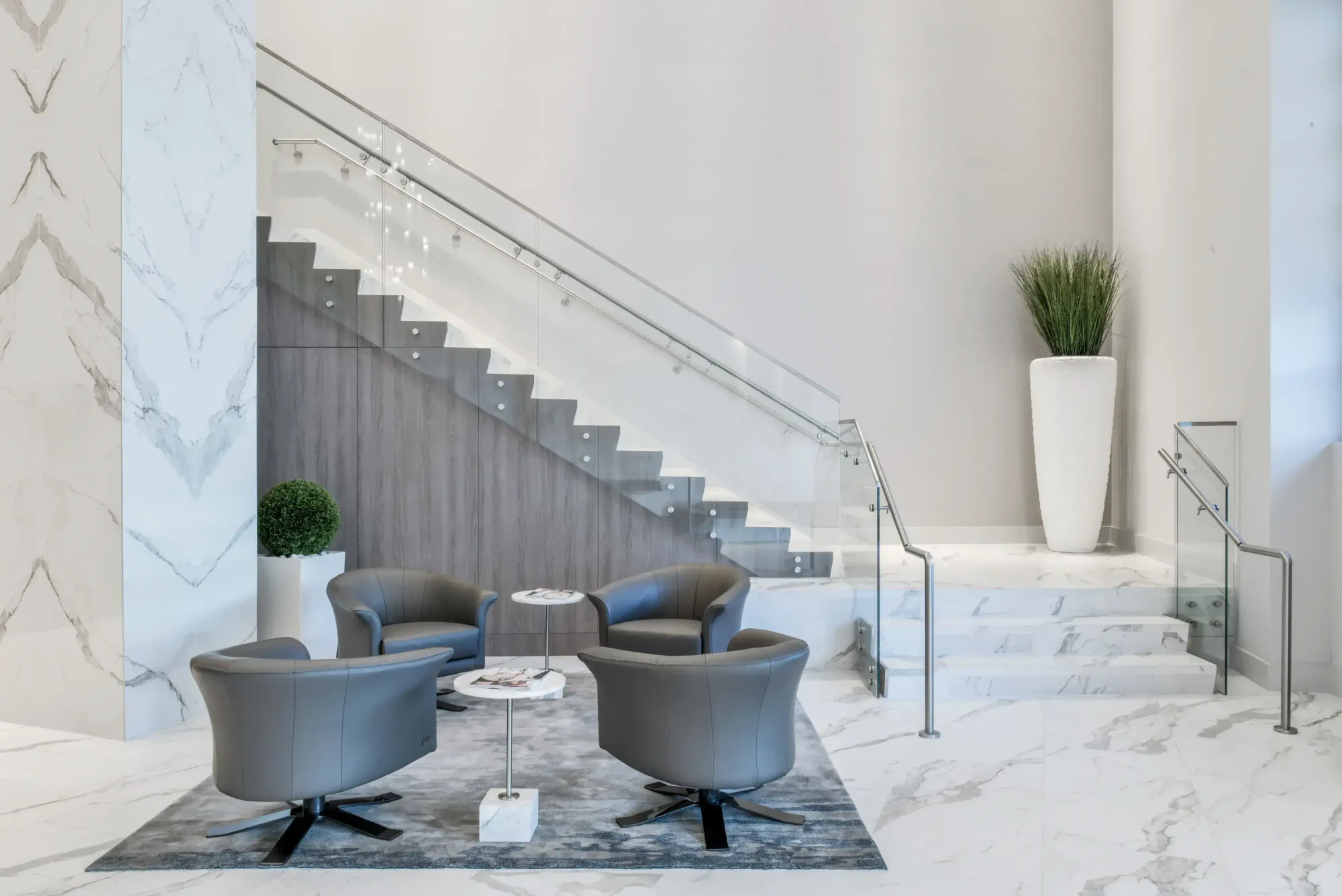 Stair landing and lounge chairs at the Diplomat Residences in Hollywood, Florida, with a glass balustrade and marble floors