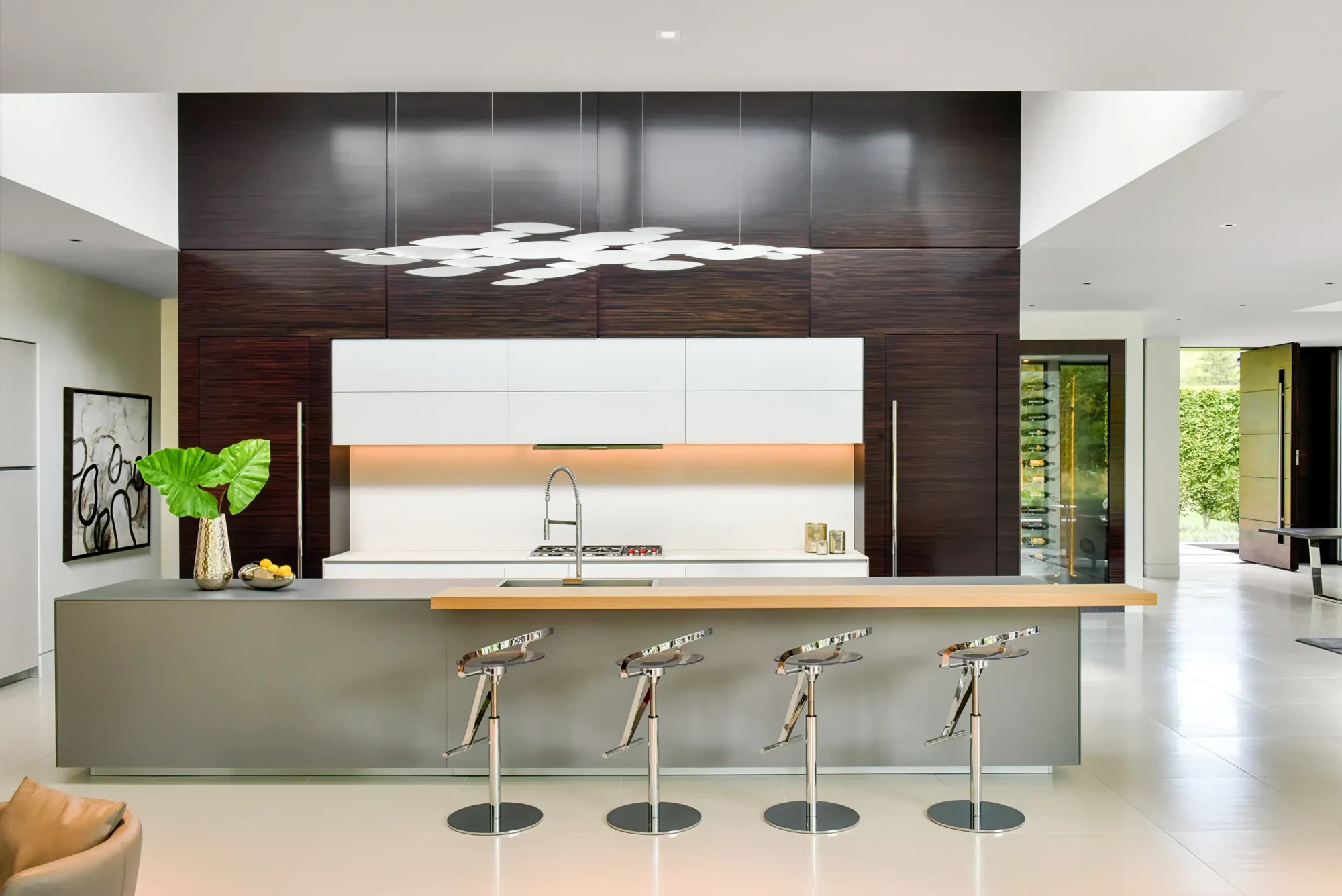Kitchen at the Richfield Residence in Davie, Florida, with dark timber cabinetry, a stainless island and sculptural ceiling light