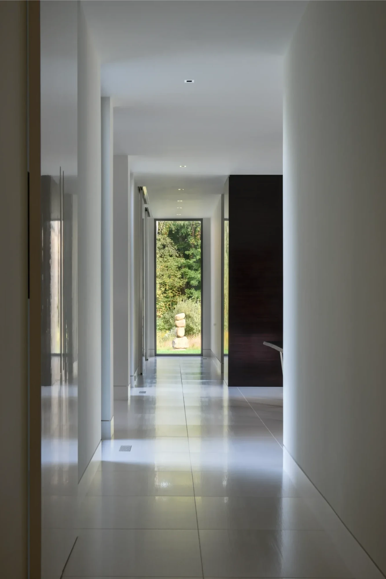Corridor at the Richfield Residence in Davie, Florida, with polished floors and a view through to the garden